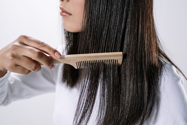 Dùng lược chải tóc để dầu dừa được thấm đều trên tóc Dùng lược chải tóc để dầu dừa được thấm đều trên tóc